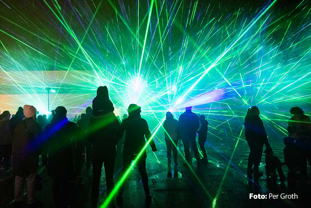 Foto på en lasershow som äger rum i centrum med ljus som strålar upp till himlen. 