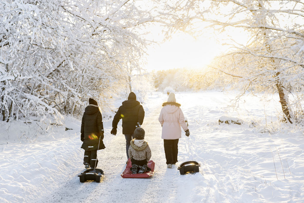 Familj som är på väg att åka pulka utomhus i snön.